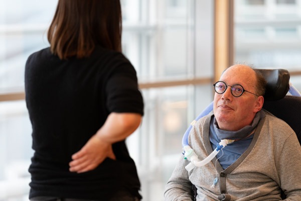 Portrait des Ohrenschmaus Vereinsgründers Franz Joseph Huainigg. Er befindet sich mit einer Frau einem Gespräch, die der Kamera den Rücken zugewandt hat.